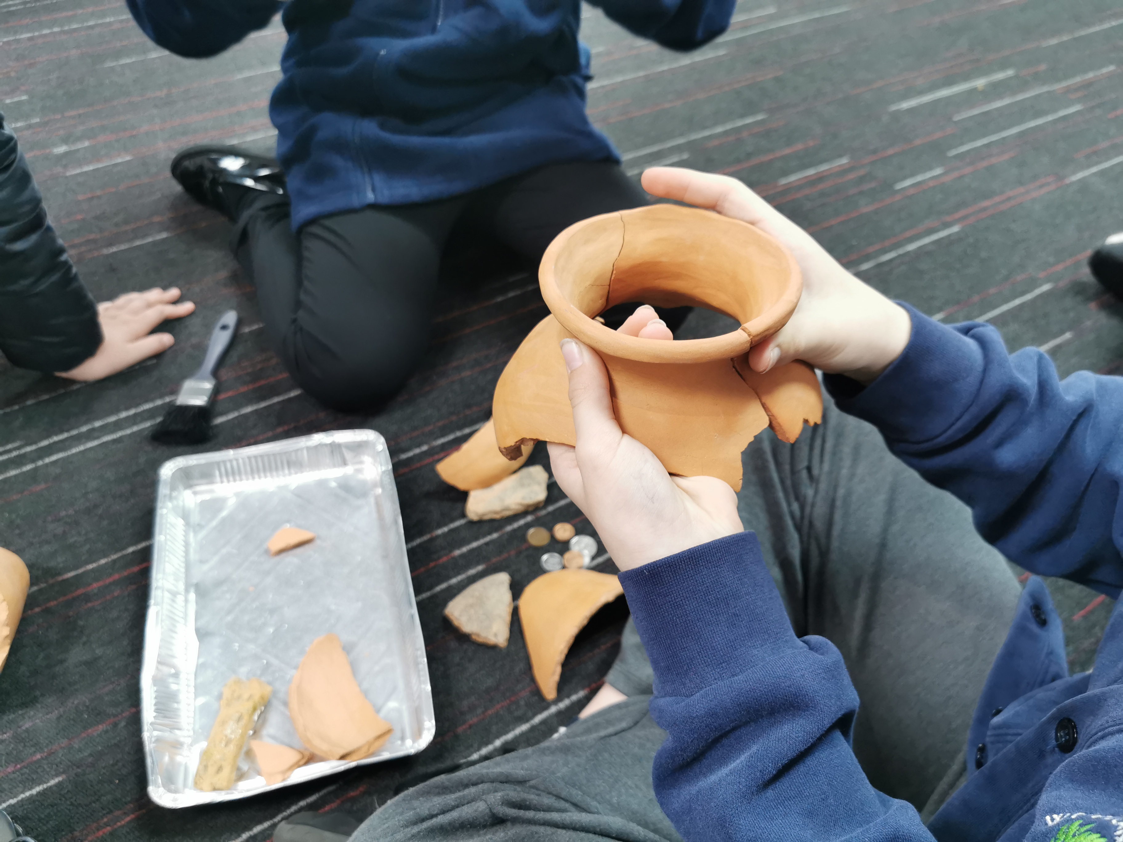 Students putting together the pottery pieces they excavated from the dig boxes.