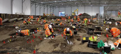 Image of team of archaeologists excavating in a large marquee 