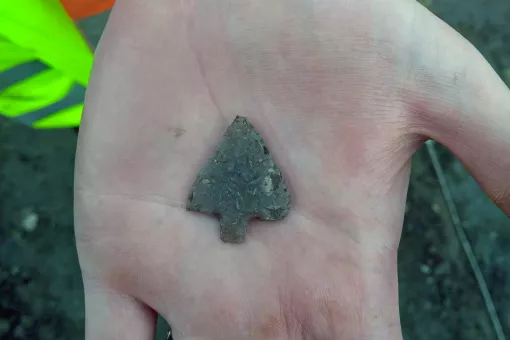 A close up of a hand holding a Prehistoric arrowhead