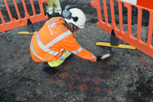 An archaeologist excavates a medieval red and black tiled floor surface