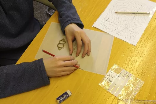 A student learning to do the archaeological illustration of a metal object