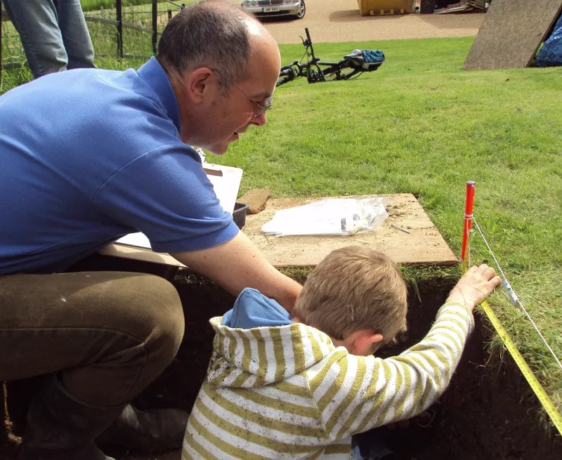 Man teaching a child how to dig a test pit.