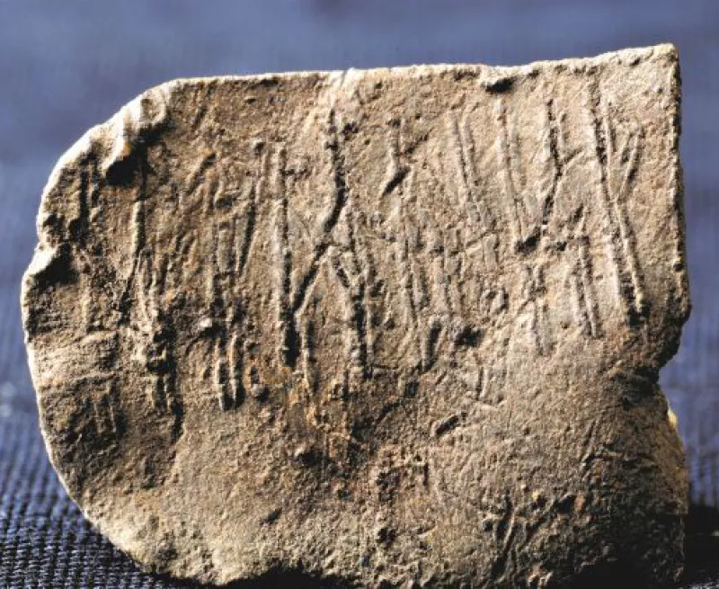 tan in colour piece of lead with runes on the flat surface
