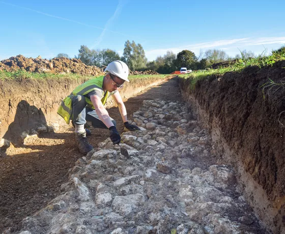 An archaeologist cleans up the chalk lumps forming a medieval metalled road surface crossing the Thames floodplain near Willow Walk. Wheel-ruts were visible, and a 14th century horseshoe was recovered from the top of this surface