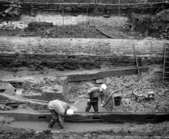 Photograph of one of the trenches that shows the extreme waterlogging found in the lower levels of the excavations. The water was pumped out during the day to allow works to continue, but the trenches were allowed to flood overnight to help preserve any timberwork and other organic finds. pumping 