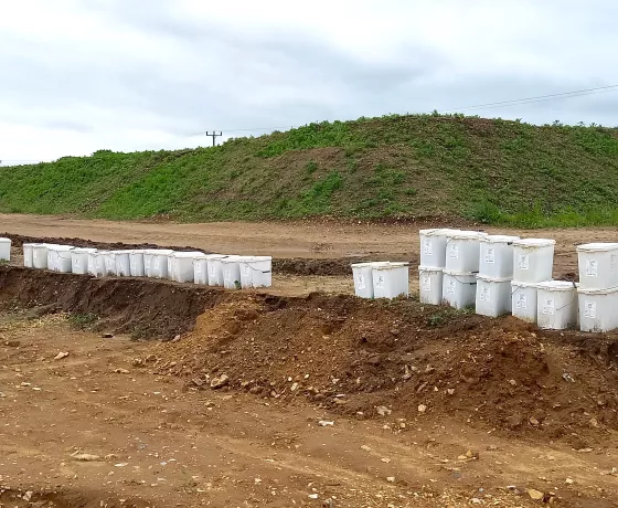 Square, white buckets sit stacked along the end of a trench.